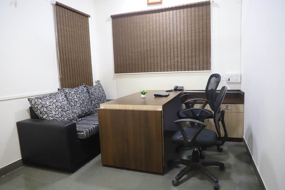 Office cabin with a wooden desk, office chairs and a sofa for client meetings