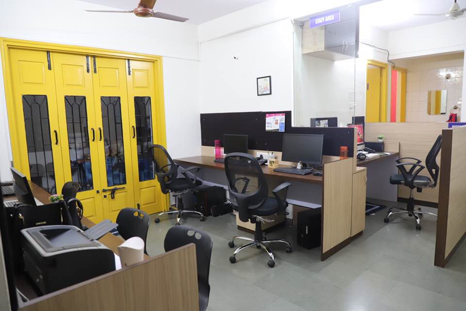 Open-plan office with computer workstations and yellow-framed glass partitions